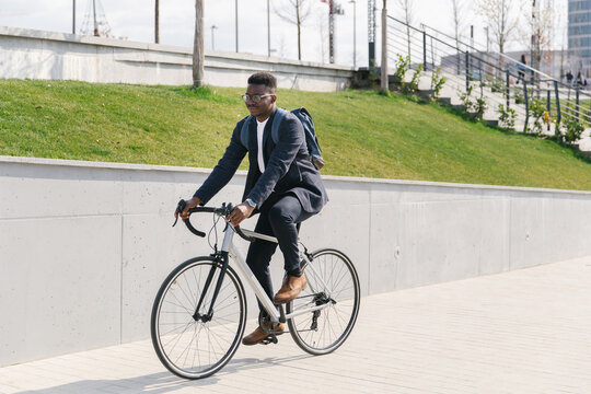 Young african american businessman riding a bicycle to work in the urban city zone 