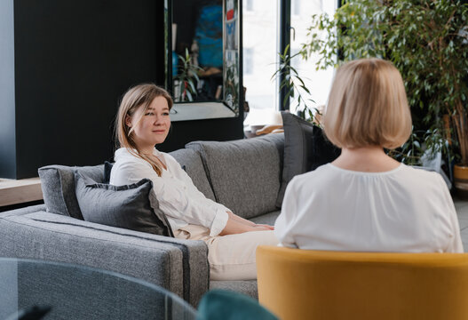 Smiling woman sitting on couch during session with psychologist