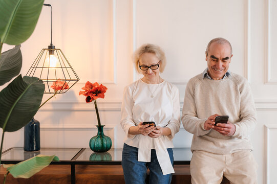Happy senior couple using smartphones at home