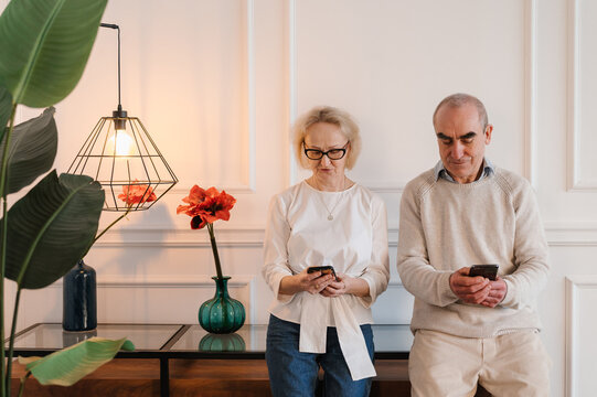 Happy senior couple using smartphones at home