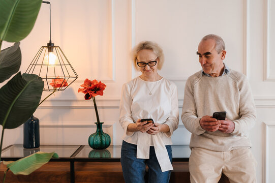 Happy senior couple using smartphones at home