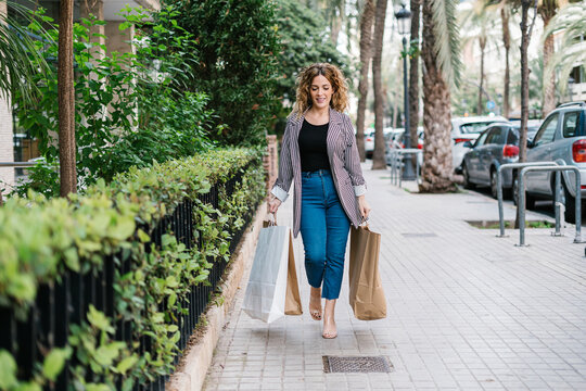 Happy woman with shopping bags walking on street
