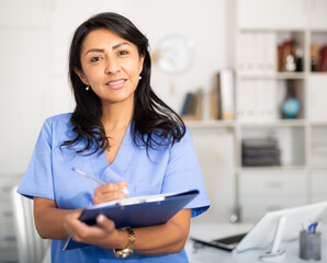 Nurse working on PC in modern private clinic with white walls