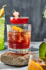 Negroni cocktail on stone podium. Sunshine with harsh shadow on vintage table. Summer day with cocktail concept. Vermouth with gin cocktail