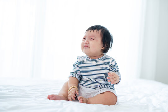 displeased cute little girl sitting on bed