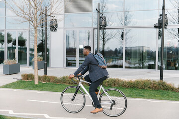Young african american businessman riding a bicycle to work in the urban city zone 