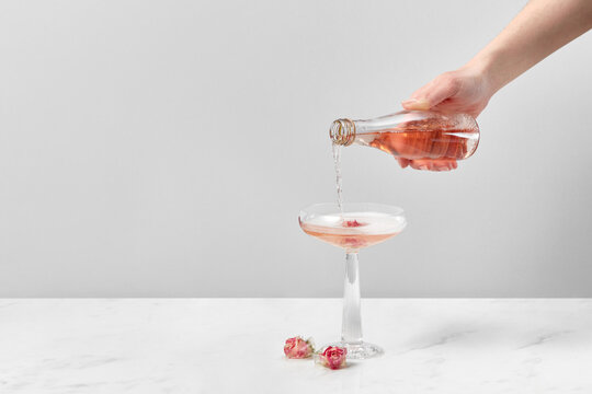 Woman pouring drink in glass with rose