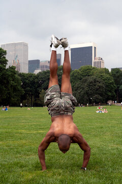 Man doing a handstand in Central park. Skyline in background