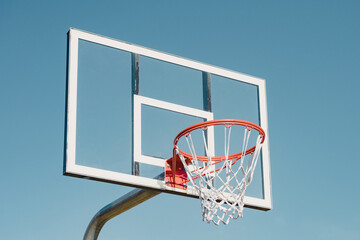 Glass basketball backboard against blue sky