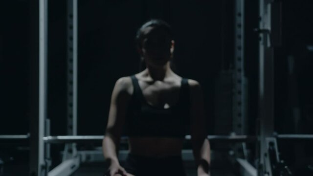 Sporty Caucasian woman sitting alone after workount in the dark gym.