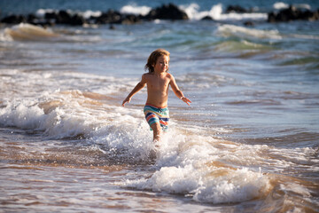 Fototapeta premium Boy kid jumping in sea waves. Jump by water sea splashes. Summer kids vacation.