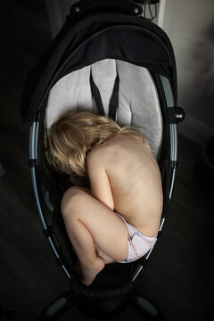 Toddler girl nestling in the baby carriage which became small for her