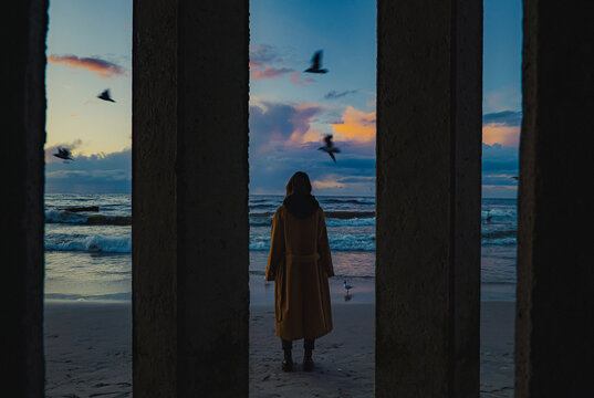 Woman in coat on the beach in the evening