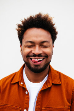 Happy black man showing tongue on white background