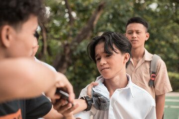 A bunch of high school delinquents bully a defenseless kid. One bully grabs him by the collar....