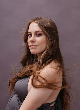 Serene pregnant female on gray background in studio
