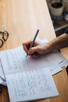 Unrecognizable man writing in notebook
