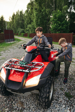 Young boys on a quad bike in a rural area.