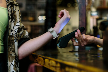 Detail shot of hand wearing a smart watch doing a wireless payment at a restaurant