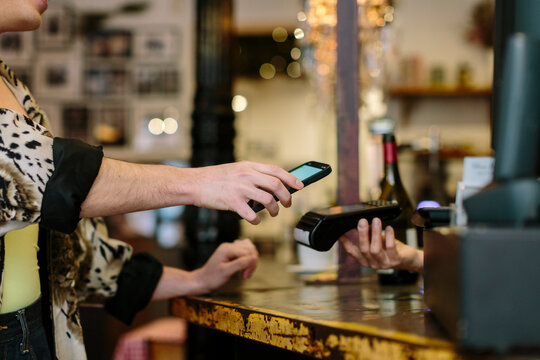 Detail shot of hand holding a smart phone doing a wireless payment at a restaurant