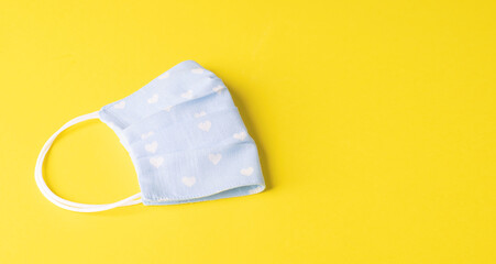 Eco-friendly reusable cloth protective mask yellow background. Homemade breathing mask, protection against corona virus
