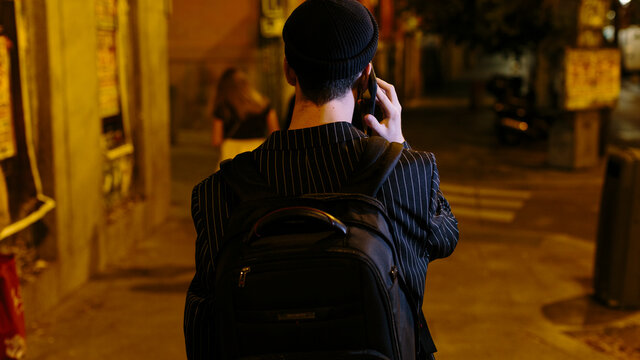 Back of young man at night  in the city speaking on the phone