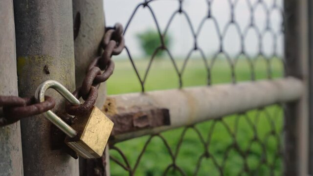 Close up old padlock and rusty chain on fence gate, Locked metal door of entrance, Close steel grate and lock,
Concept lockdown and safety, Handheld show motion shot, Shallow depth of field.