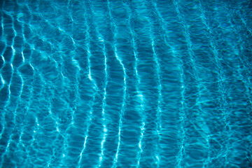 Blue pool water background. Blurred transparent clear calm water surface texture. Water waves in sunlight with copy space.