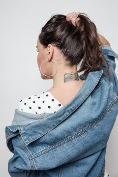 Woman holds her hair up exposing a camera tattoo on her neck