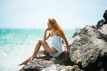 Fototapeta na wymiar Young sexy woman at sea. Summer beach sensual girl. Girl in white dress on tropical beach vacation.
