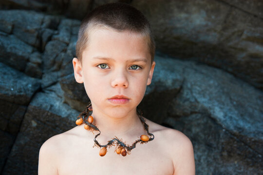 Portrait of a boy at the beach wearing a seaweed necklace