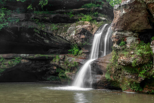 Water cascades down tiers of worn sandstone at the Upper Falls, a beautiful waterfall at Old Man&rsquo;s Cave in Hocking Hills State Park, Ohio seen in profile from the side.