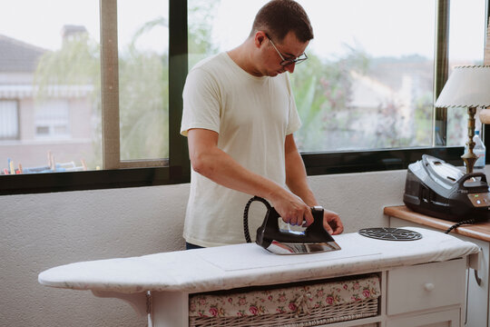 Man with iron in hand performing household chores
