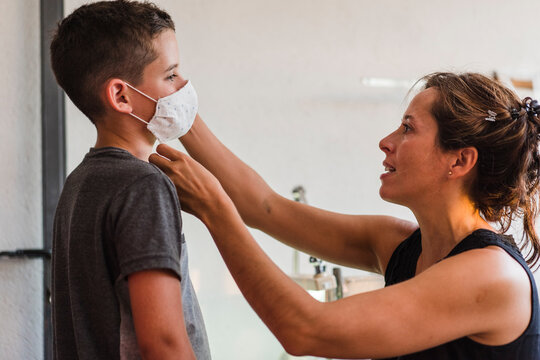 Mother putting a cloth mask on her son's face