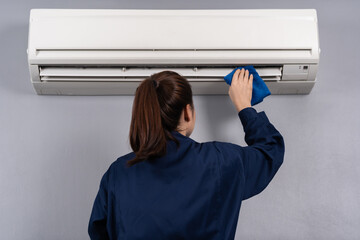 female technician service cleaning air conditioner with cloth