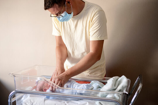 Man with a mask tucking a baby