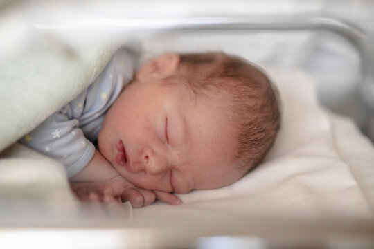 Newborn baby sleeping in printed pyjamas