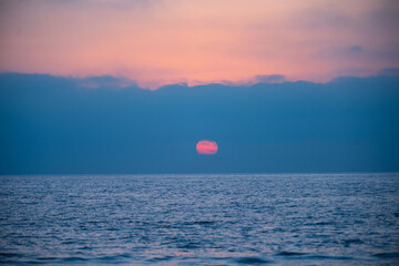 Calm sea with sunset sky and sun through the clouds over. Ocean and sky background, seascape.