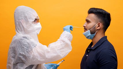 Medical worker in protective suit taking Nasal swab from a potentially infected young guy. Corona...