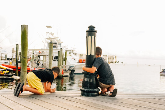 Backs of two boys looking down into the water. 