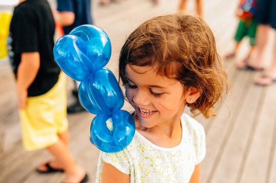 Balloon animal in the shape of a parrot on a little girl's shoulder. 