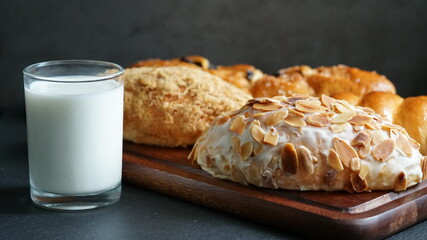 A glass of milk and various kinds of pastries on wooden board