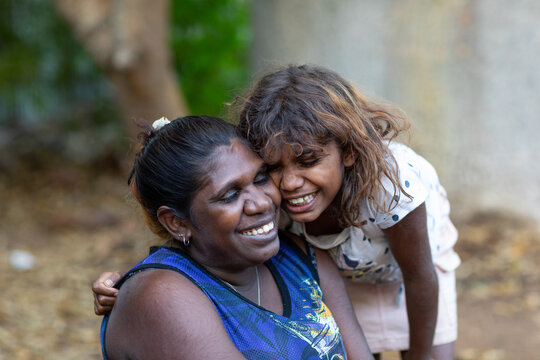 Smiling Indigenous mother and daughter with their faces close together