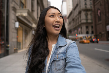 Fototapeta premium Young Asian woman in city walking face time video chatting