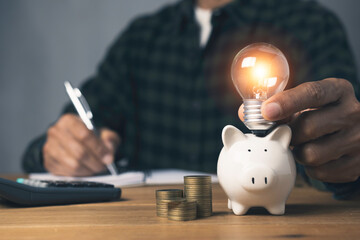 Holding light bulb piggy bank with stack coins and whiting account saving money investment an idea concept. - obrazy, fototapety, plakaty