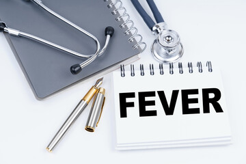 On the table are a stethoscope, a pen and a notebook with the inscription - FEVER