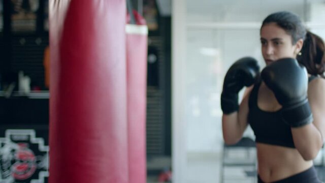 Boxing, woman fighter trains her punches, beats a punching bag, training day in the boxing gym, strength fit body, the girl strikes fast.