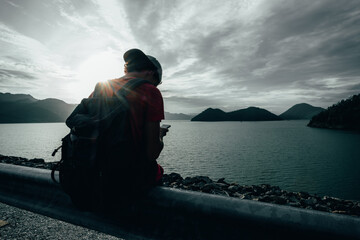 Fototapeta premium young teen Caucasian boy hipster man adult backpacker enjoying camera on beautiful landscape scenery view jungle mountains forest at Kanchanaburi water river dam National Park, Thailand.