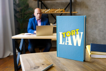 Attorney holds LAW TORT book. A tort occurs when someone commits a wrong against another person - obrazy, fototapety, plakaty