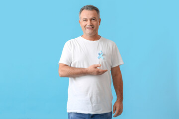 Mature man with blue ribbon on color background. Prostate cancer awareness concept - obrazy, fototapety, plakaty